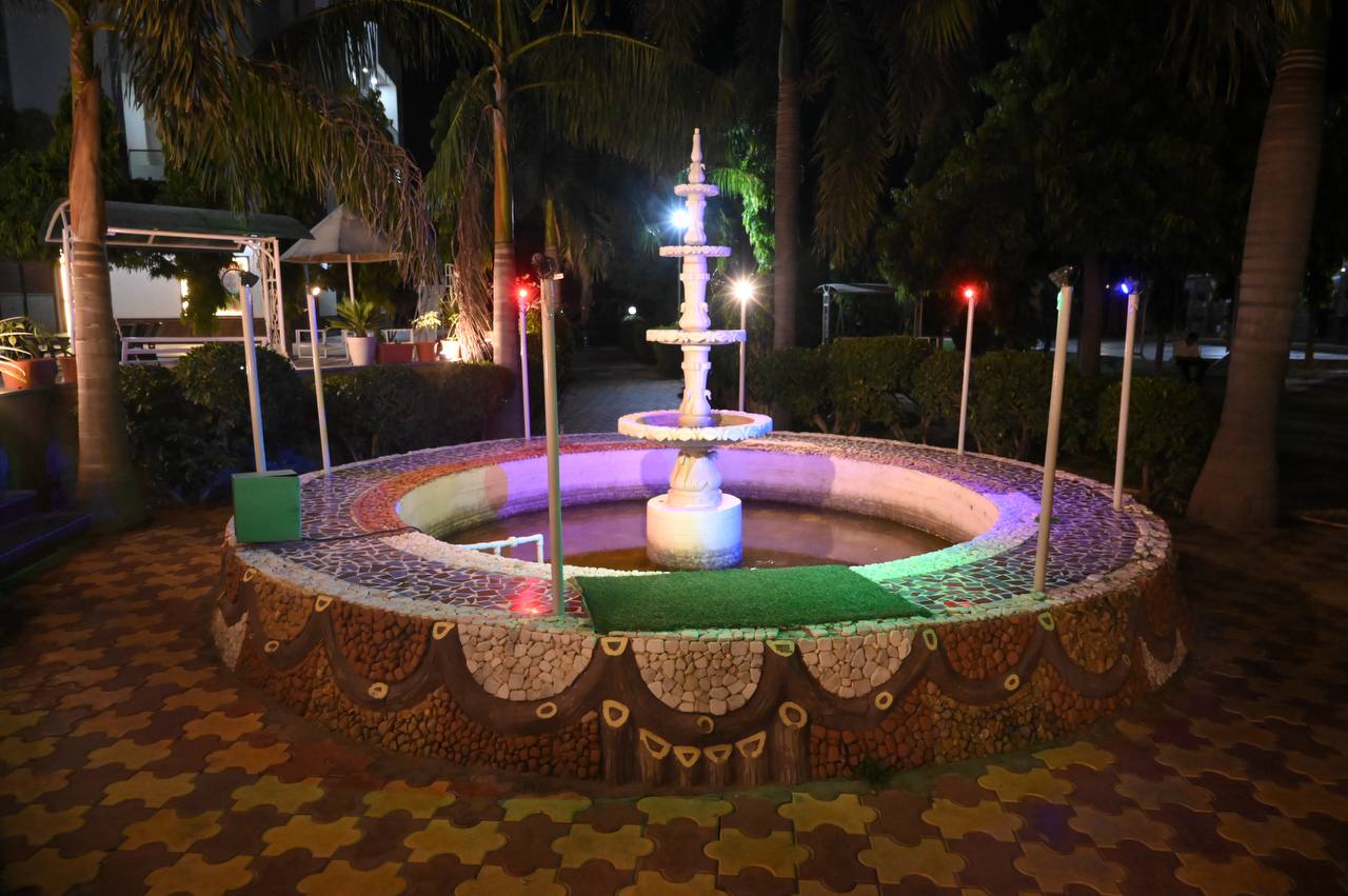 Decorative circular garden fountain illuminated in the evening.