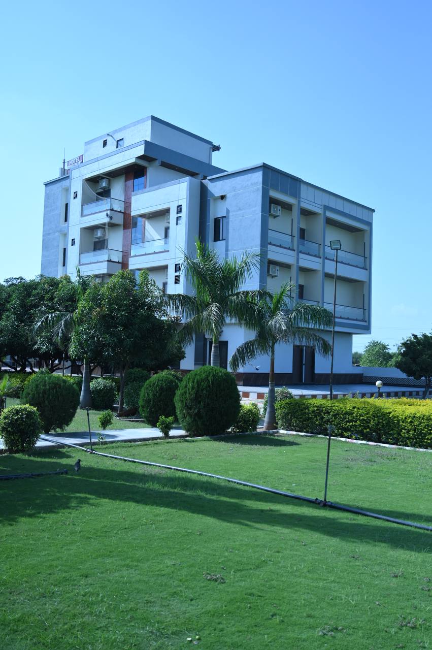 Hotel building behind palms and landscaped lawn at Green Valley Resort.
